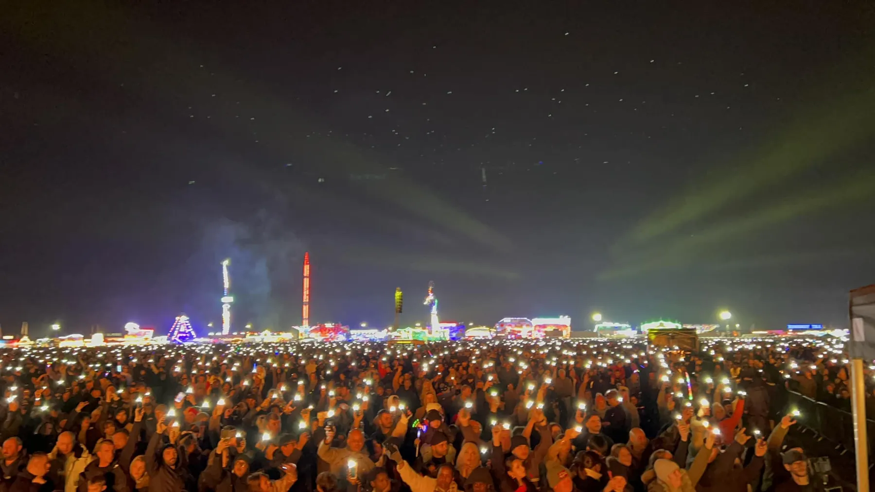 Crowd holding lights in the air before the main fireworks
